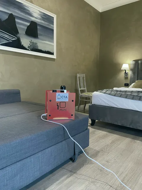 L’ICUBE mini con l’adesivo CTA su un divano di una camera d’albergo vuota