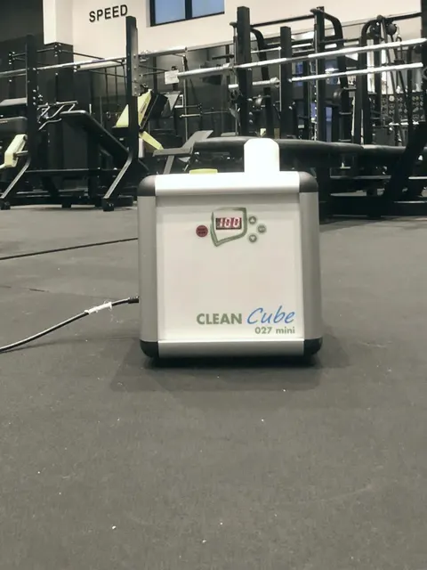 L’atomizzatore Clean Cube sul pavimento di una palestra vuota, davanti agli attrezzi